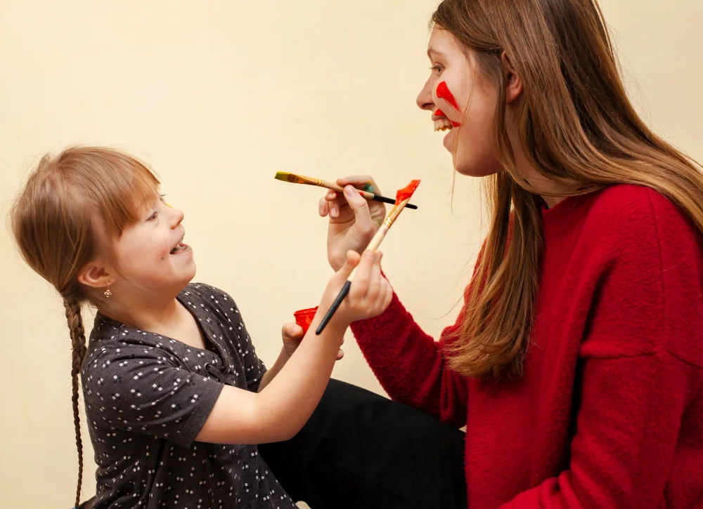happy woman girl with down syndrome painting each other s faces copy
